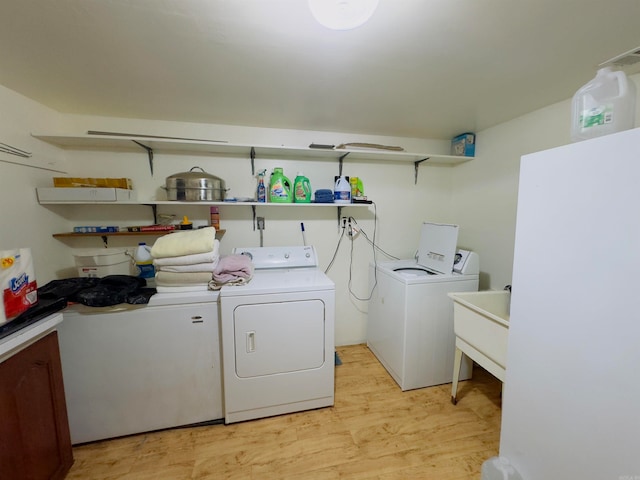 washroom featuring independent washer and dryer, light wood-type flooring, and sink