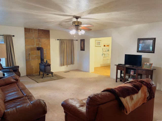 living room with light colored carpet, a wood stove, and ceiling fan