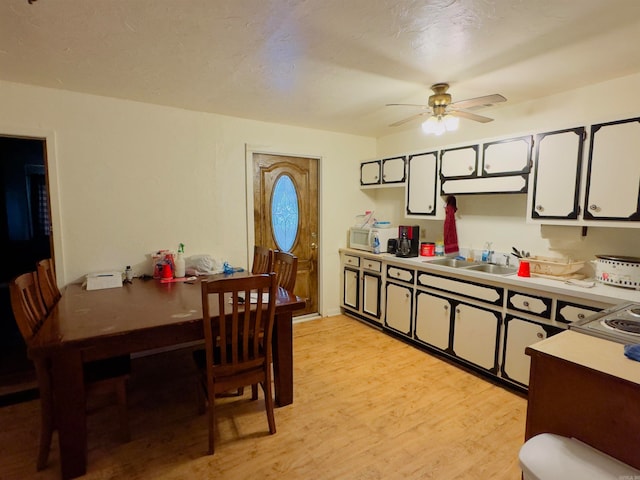 kitchen with white cabinetry, ceiling fan, sink, and light hardwood / wood-style flooring