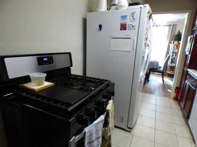 kitchen with black gas range, light hardwood / wood-style flooring, and white fridge