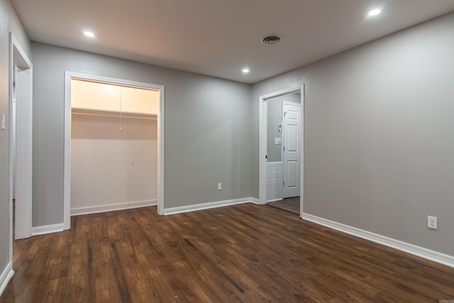 unfurnished bedroom with a closet, dark hardwood / wood-style flooring, and a spacious closet