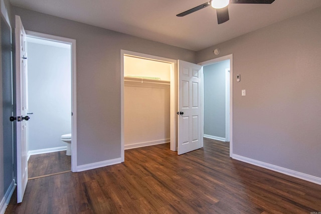 unfurnished bedroom featuring ensuite bathroom, ceiling fan, a spacious closet, dark hardwood / wood-style flooring, and a closet