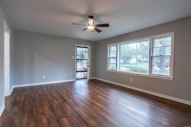 empty room with plenty of natural light, ceiling fan, and dark hardwood / wood-style flooring