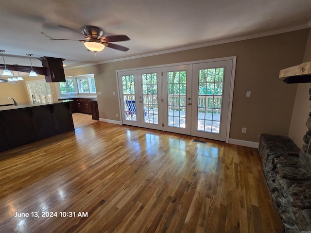 unfurnished living room with a wealth of natural light, sink, french doors, and light hardwood / wood-style flooring