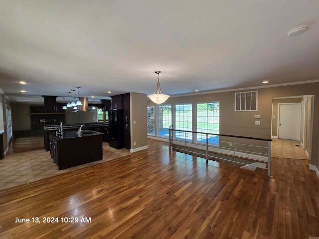 kitchen featuring sink, black fridge, dark hardwood / wood-style flooring, a kitchen island with sink, and dark brown cabinets