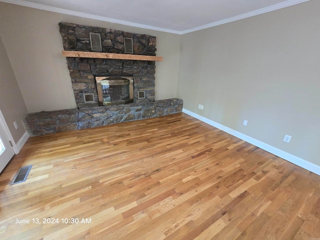 unfurnished living room with hardwood / wood-style flooring, ornamental molding, and a fireplace