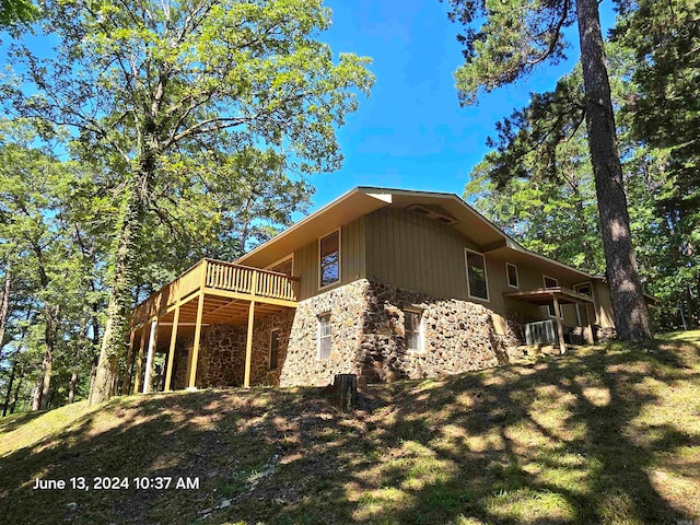 view of side of home with a wooden deck and a yard