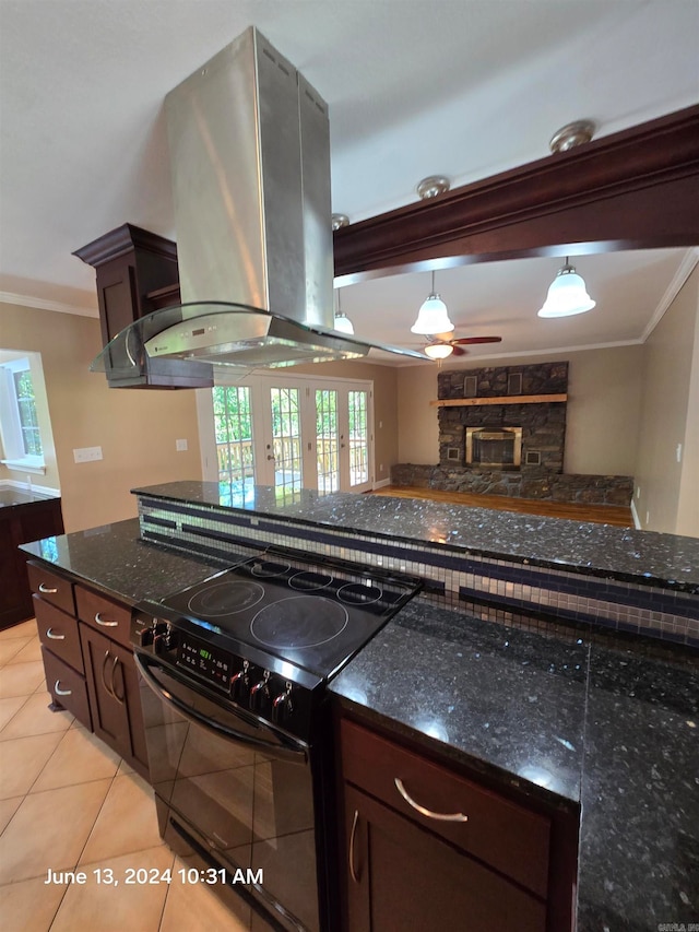 kitchen with ornamental molding, dark stone counters, wall chimney exhaust hood, light tile patterned floors, and black electric range