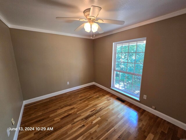 empty room featuring crown molding, ceiling fan, and dark wood-type flooring