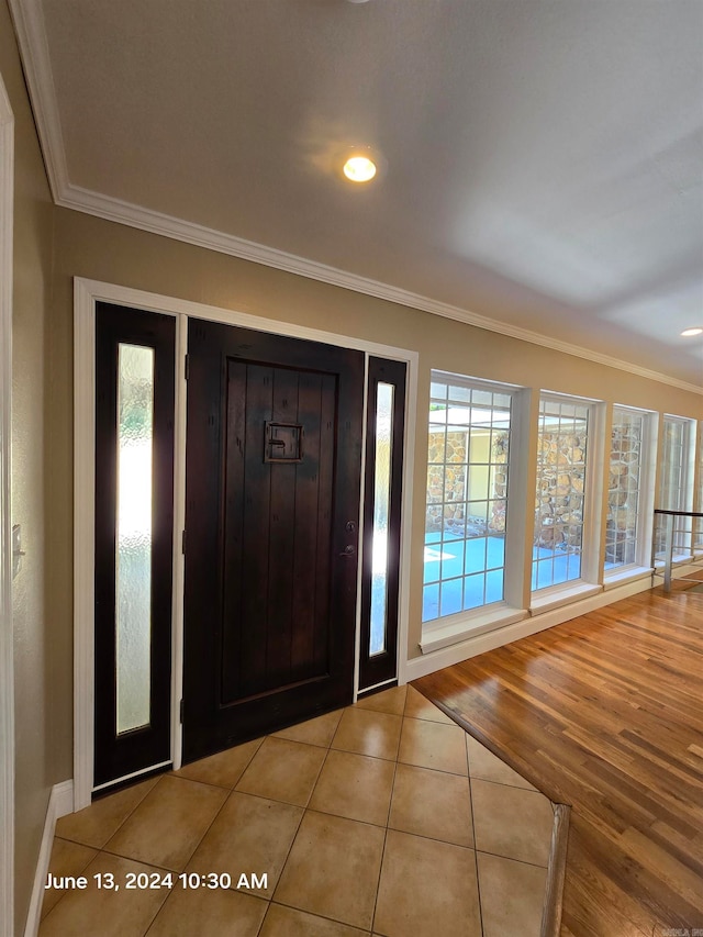 foyer featuring light wood-type flooring and crown molding