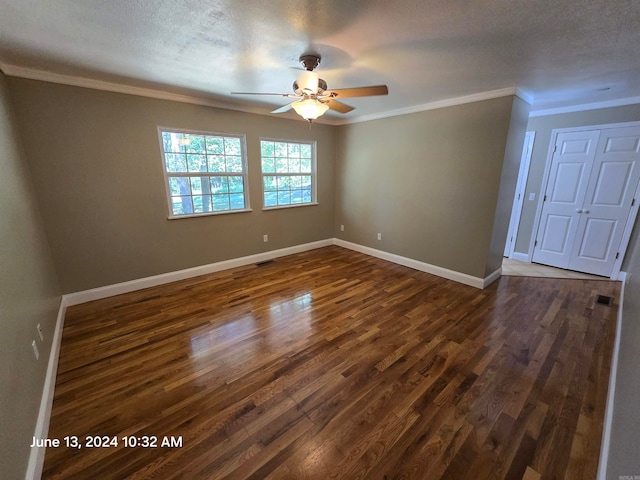 spare room featuring a textured ceiling, dark hardwood / wood-style flooring, and crown molding