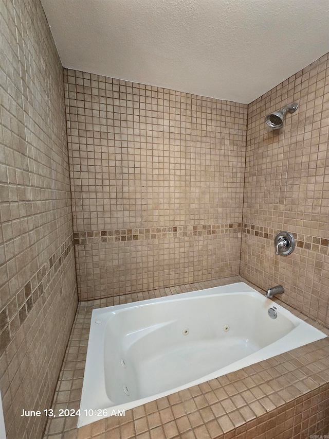 bathroom with tiled shower / bath combo and a textured ceiling