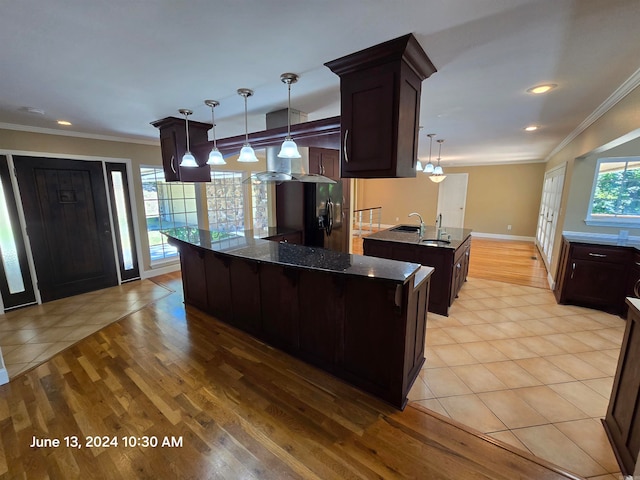 kitchen featuring a center island with sink, decorative light fixtures, light hardwood / wood-style floors, and dark brown cabinets