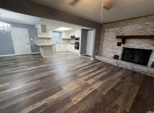 unfurnished living room featuring a textured ceiling, sink, a chandelier, and dark hardwood / wood-style floors