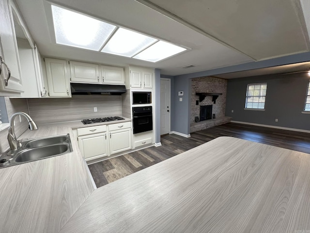 kitchen featuring dark hardwood / wood-style flooring, a fireplace, black appliances, sink, and white cabinets