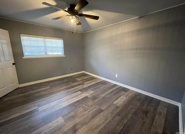 empty room with dark hardwood / wood-style flooring, wooden walls, ceiling fan, and crown molding