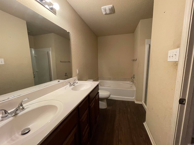 full bathroom featuring vanity, a textured ceiling, shower with separate bathtub, hardwood / wood-style floors, and toilet