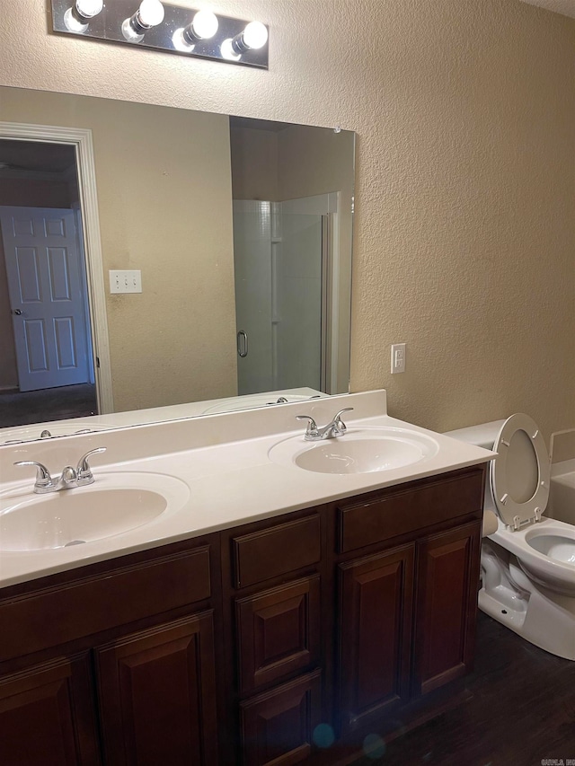 bathroom with hardwood / wood-style flooring, vanity, a shower with shower door, and toilet