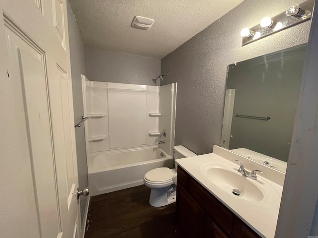 full bathroom featuring hardwood / wood-style floors, vanity, washtub / shower combination, toilet, and a textured ceiling