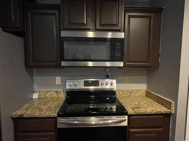 kitchen featuring light stone countertops, dark brown cabinetry, and appliances with stainless steel finishes