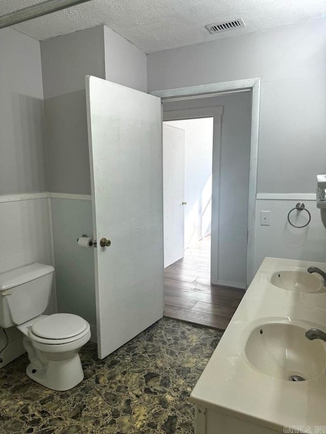 bathroom with vanity, wood-type flooring, a textured ceiling, and toilet