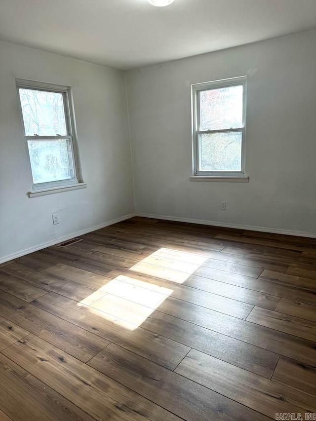 spare room featuring dark hardwood / wood-style flooring and plenty of natural light