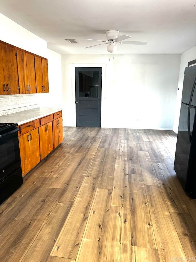 kitchen with black appliances, ceiling fan, and hardwood / wood-style floors