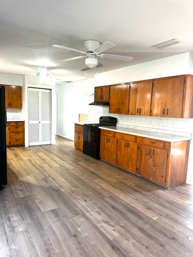 kitchen featuring decorative backsplash, ceiling fan, black appliances, and dark hardwood / wood-style floors