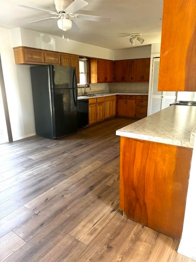 kitchen with wood-type flooring, tasteful backsplash, ceiling fan, and black appliances