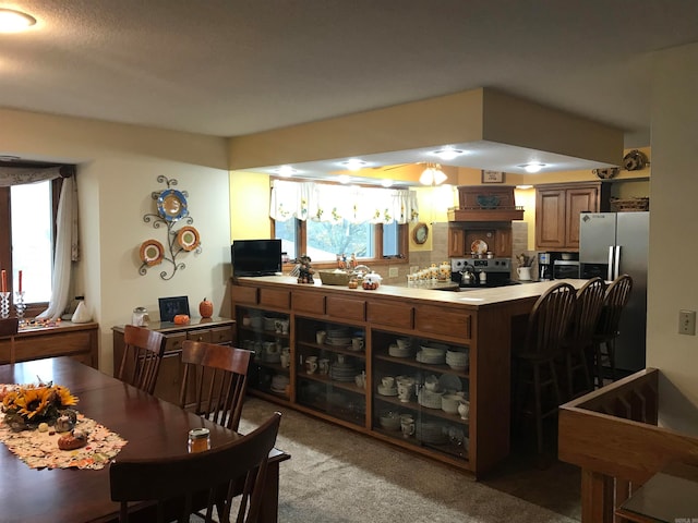 kitchen featuring black appliances, decorative backsplash, kitchen peninsula, and carpet floors