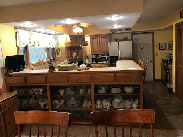 kitchen with stainless steel appliances, tile counters, and ceiling fan