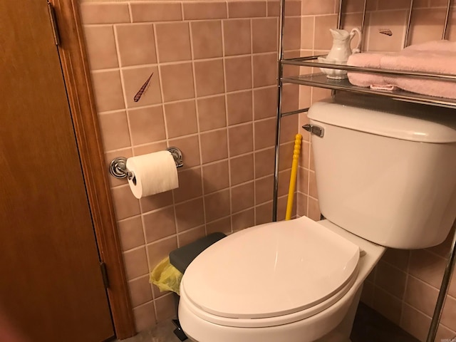 bathroom featuring toilet and tile walls