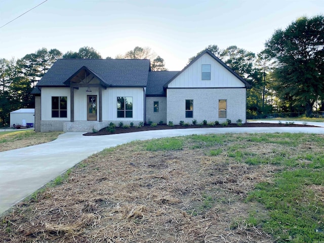 modern farmhouse style home with roof with shingles and board and batten siding