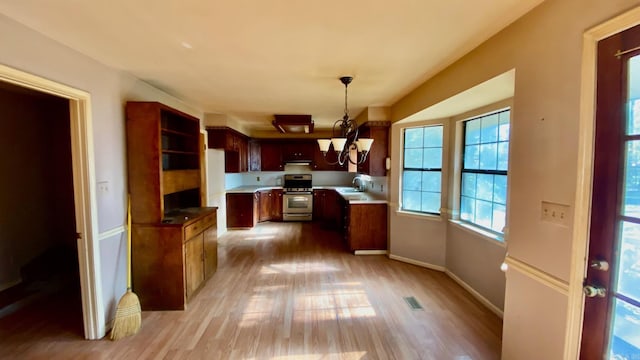 kitchen featuring pendant lighting, hardwood / wood-style floors, an inviting chandelier, sink, and gas stove