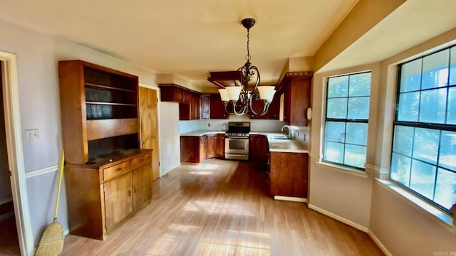 kitchen featuring pendant lighting, stainless steel gas stove, a wealth of natural light, and sink