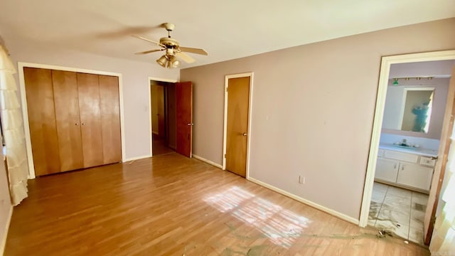 unfurnished bedroom with connected bathroom, ceiling fan, hardwood / wood-style floors, and sink