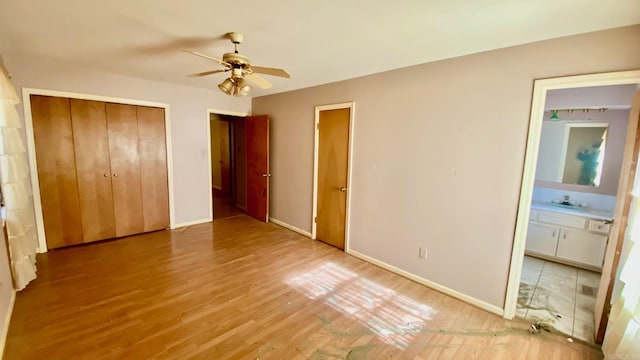 unfurnished bedroom featuring wood-type flooring, ensuite bath, ceiling fan, and sink