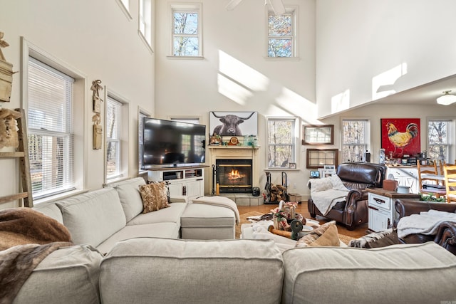 living room featuring a tile fireplace, a towering ceiling, and wood-type flooring