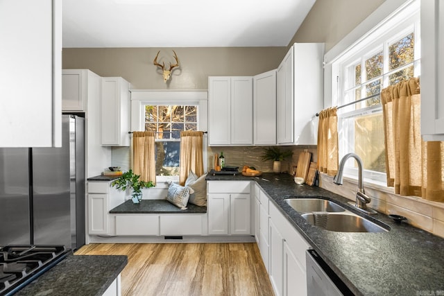 kitchen with white cabinetry, sink, stainless steel appliances, tasteful backsplash, and light wood-type flooring