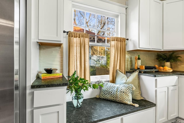 interior space with white cabinetry, stainless steel fridge, and tasteful backsplash