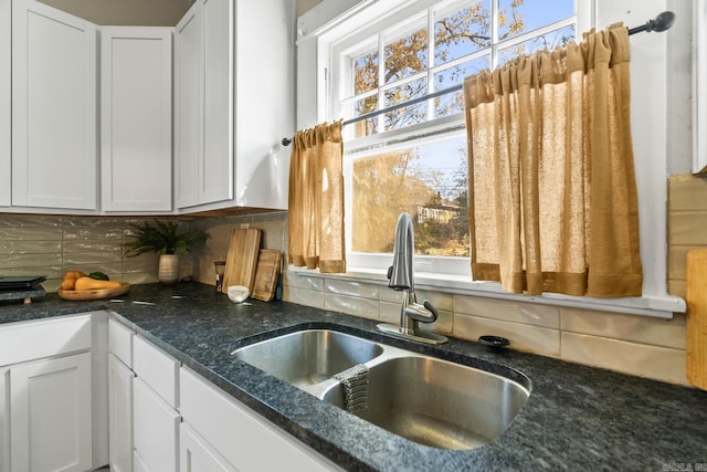 kitchen featuring white cabinets, decorative backsplash, and sink