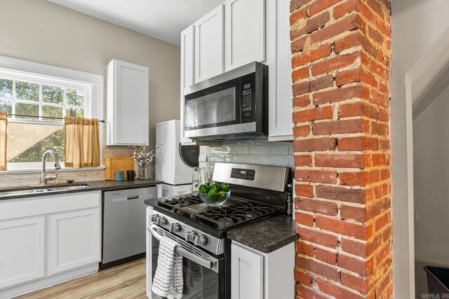 kitchen with white cabinets, appliances with stainless steel finishes, light hardwood / wood-style flooring, and sink