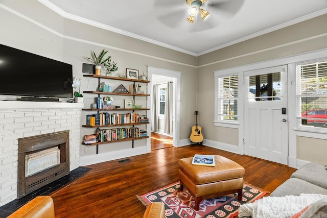 living room with a fireplace, wood-type flooring, ceiling fan, and crown molding