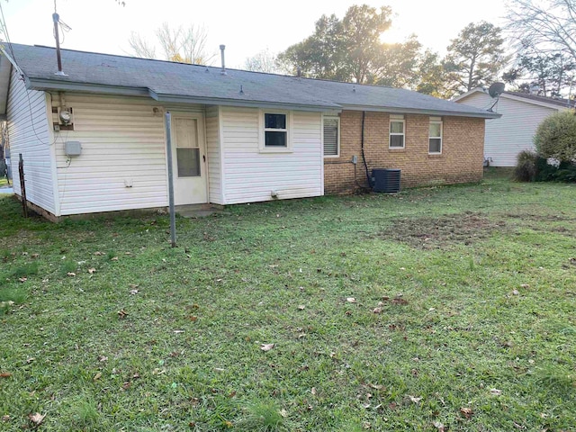 rear view of property with cooling unit and a lawn