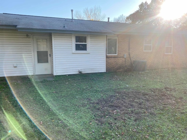 back of property featuring central AC unit and a lawn