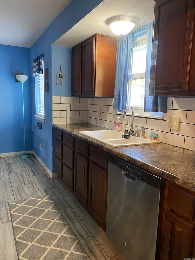 kitchen featuring dark brown cabinetry, sink, light hardwood / wood-style flooring, stainless steel dishwasher, and decorative backsplash