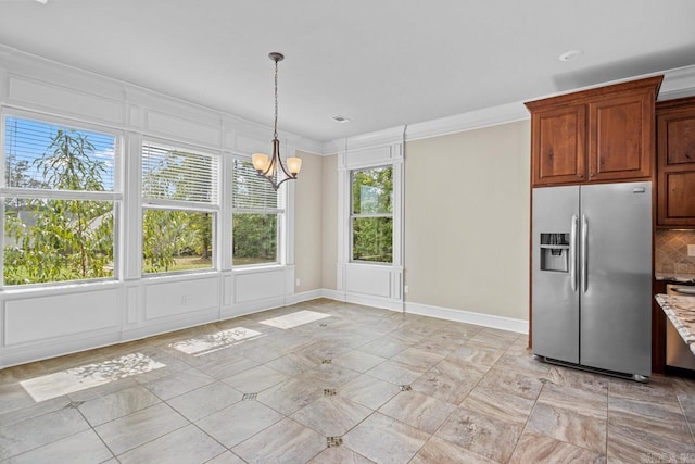 unfurnished dining area featuring crown molding and an inviting chandelier