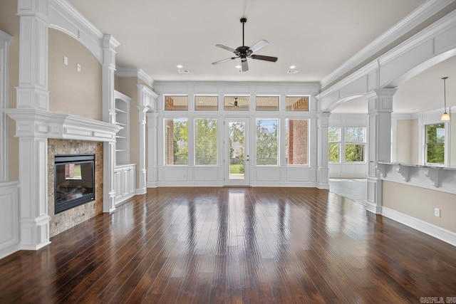 unfurnished living room with decorative columns, ceiling fan, crown molding, built in features, and dark hardwood / wood-style floors