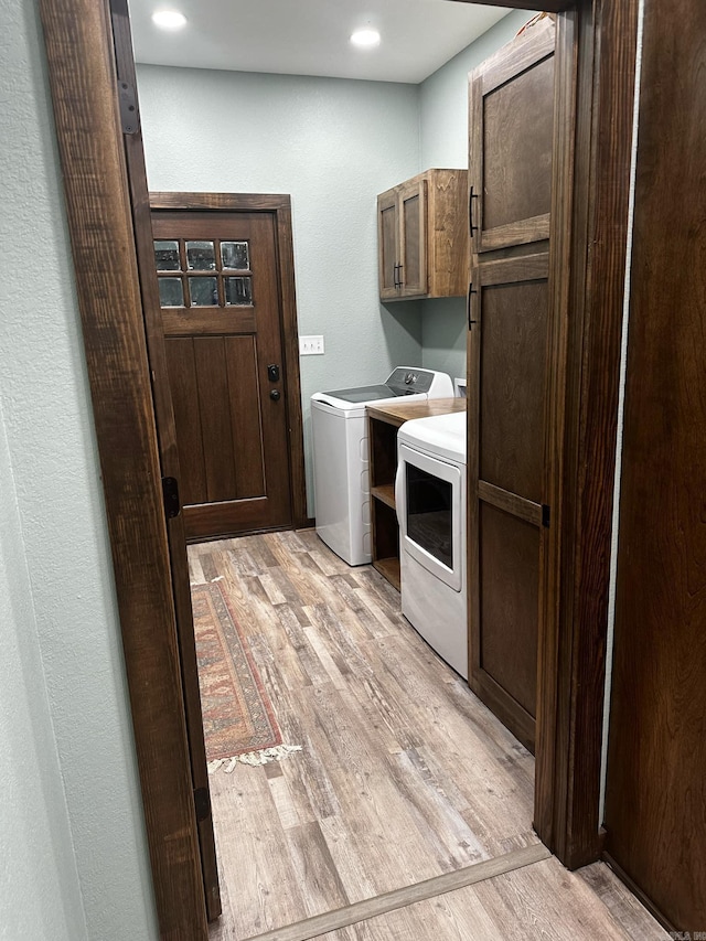 clothes washing area with cabinets, light wood-type flooring, and washing machine and dryer