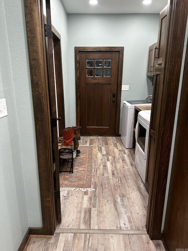 clothes washing area featuring cabinets, washing machine and dryer, and light hardwood / wood-style flooring